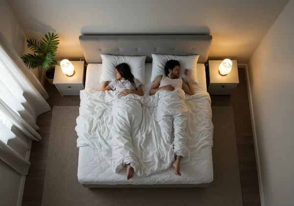 Couple sleeping peacefully with space on a King size bed.