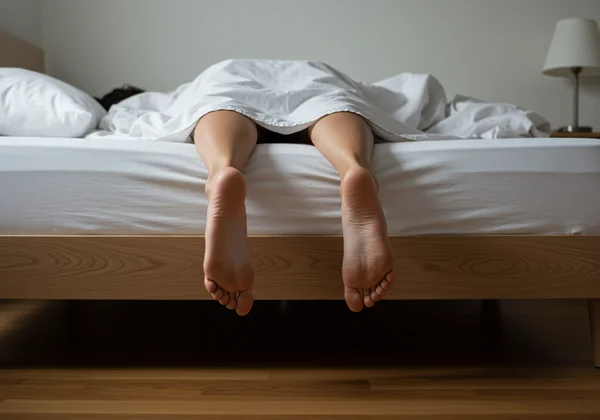 Tall person's feet dangling off the end of a too-short mattress